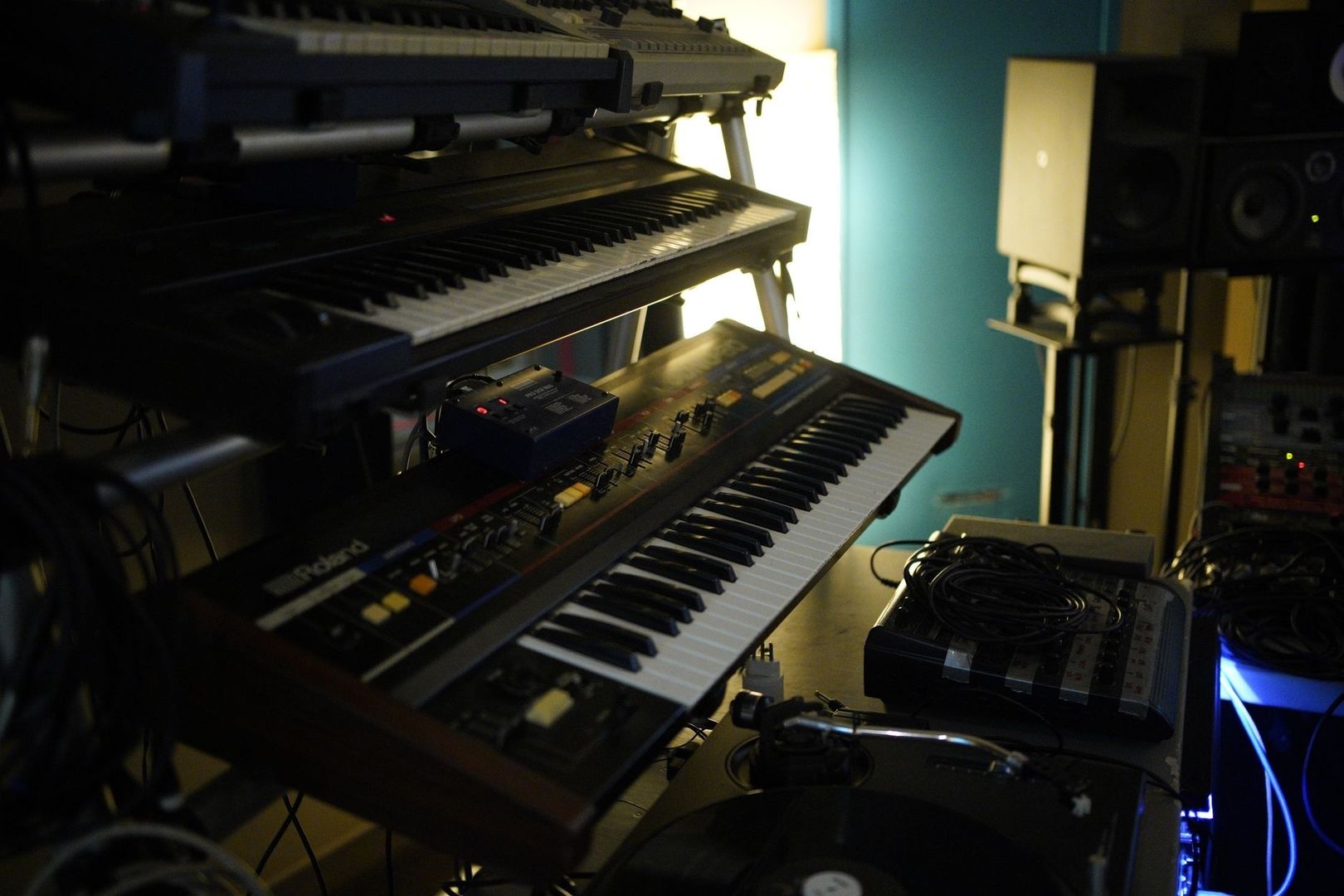 Mehrere analoge Synthesizer und Keyboards in einem dunklen Musikstudio