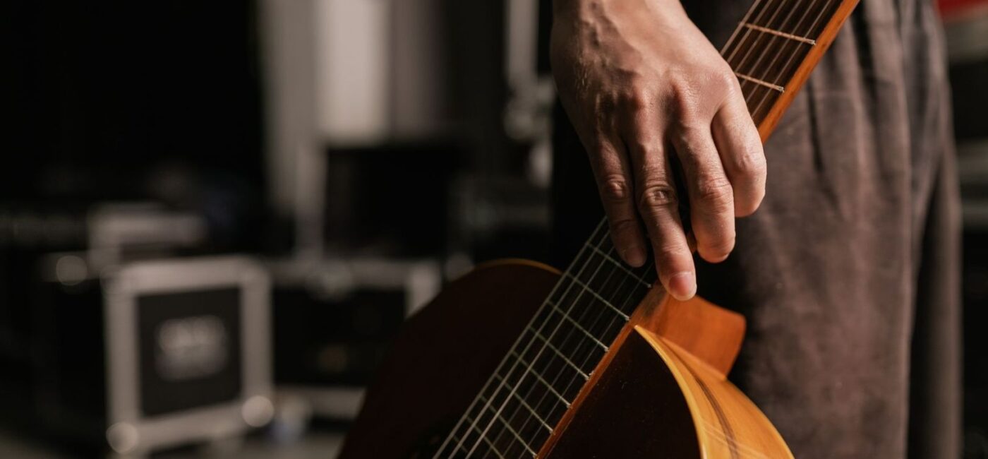 Nahaufnahme einer Hand an einer akustischen Gitarre auf der Bühne